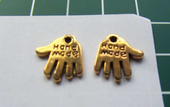 bedeltje: goudkleurig handje met "handmade" erop